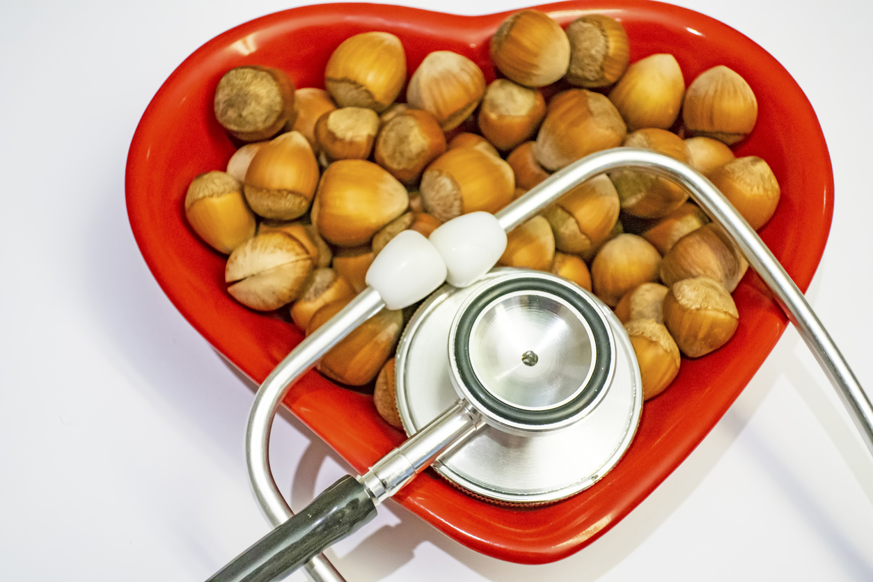 shelled hazelnut heart figured on red plate and stethoscope for human health